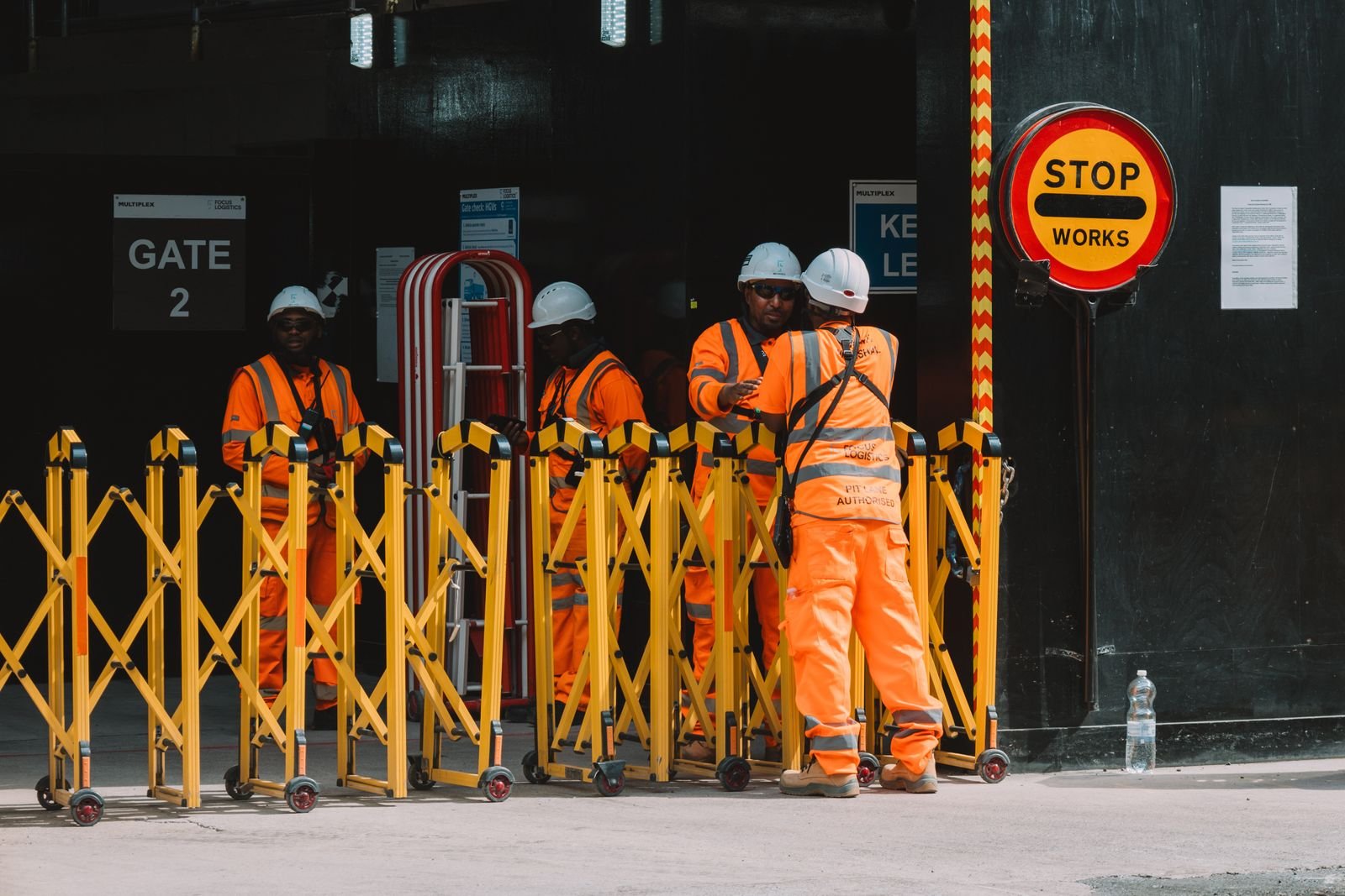 Construction workers in high-visibility clothing at a London site gate