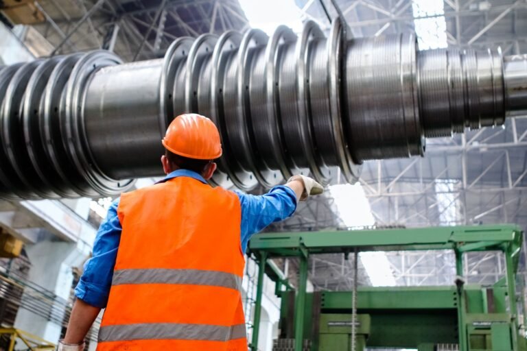 Engineer in a hard hat and high-visibility vest inspecting large industrial machinery