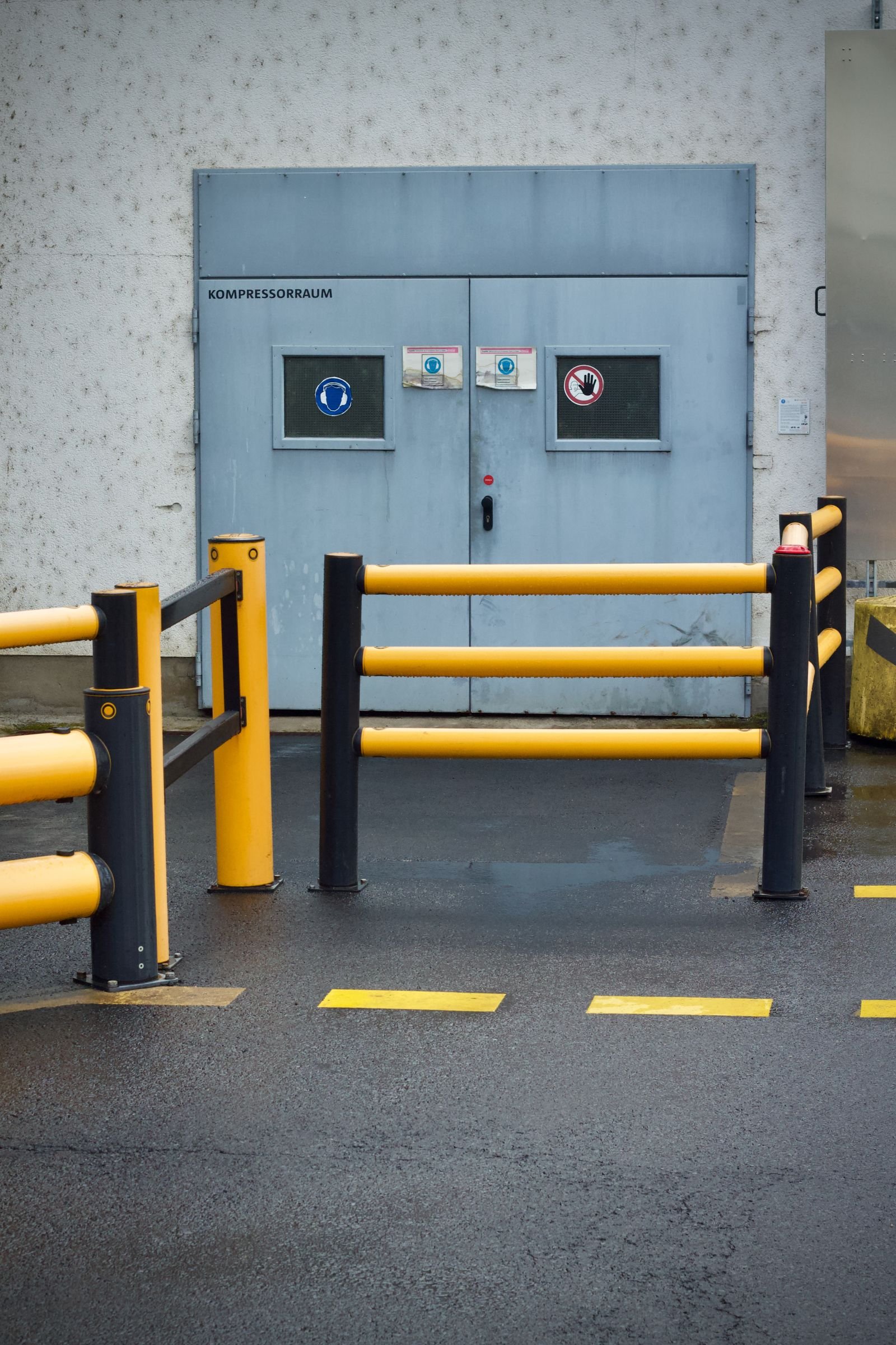 Plant room door with yellow safety barriers at an industrial site