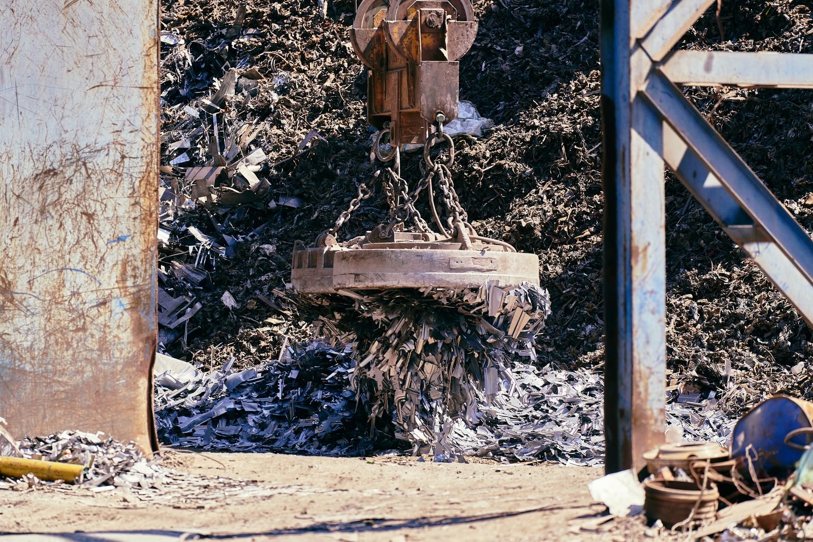 Magnet crane lifting scrap metal at a recycling yard